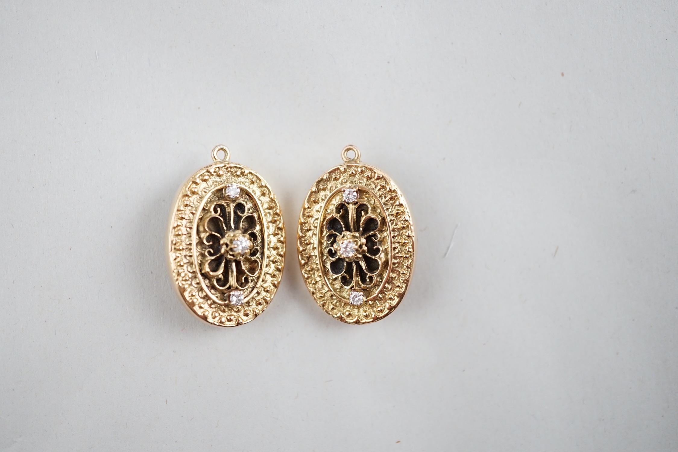 A modern pair of 9ct gold and three stone diamond set oval pendant brooches